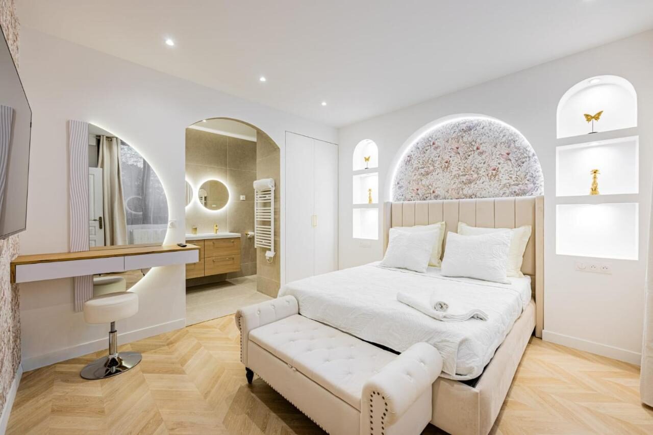 Chambre lumineuse d'Arche Royale avec tête de lit arquée et parquet